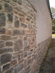 lime repointed stonework beneath a rendered cob wall